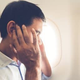 Man experiencing ear pressure on a plane.