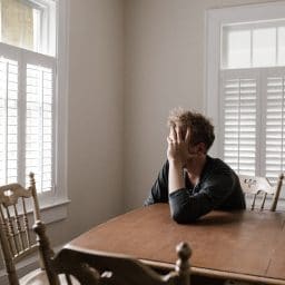 Frustrated man sitting at kitchen table.