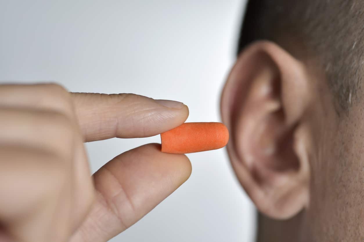 Man inserting an earplug into his ear for hearing protection.