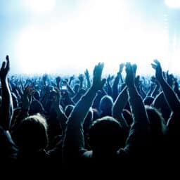 A crowd of people with raised arms during a music concert with an amazing light show.