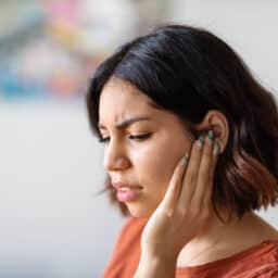 woman experience tinnitus holding her ear