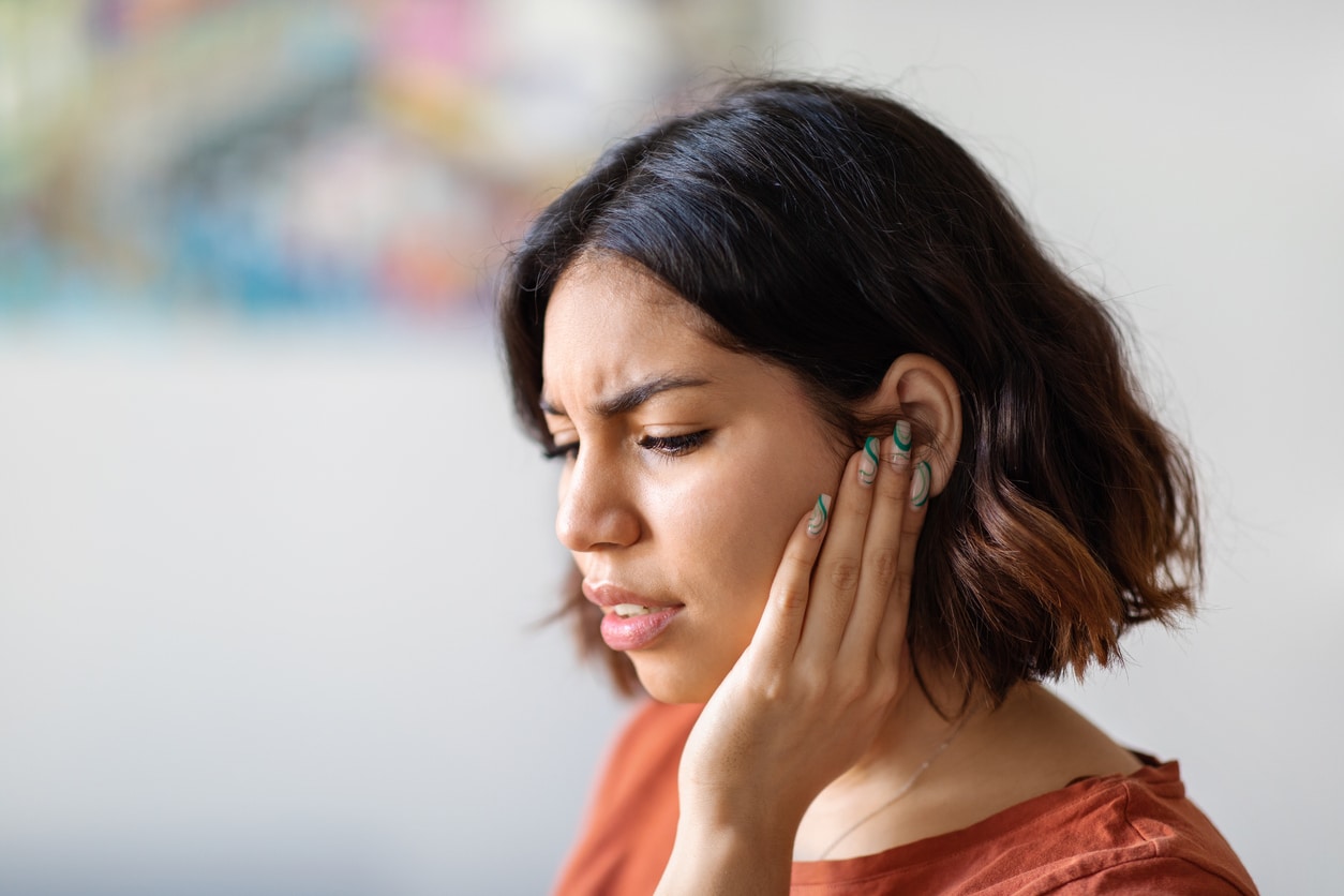 Woman experience tinnitus holding her ear