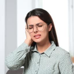 Woman with tinnitus placing her hand over her ears