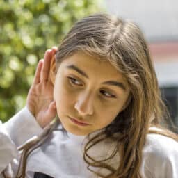 Young girl cups ear to hear