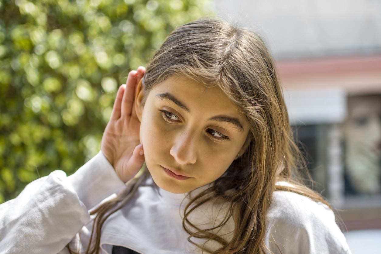 Young girl cups ear to hear