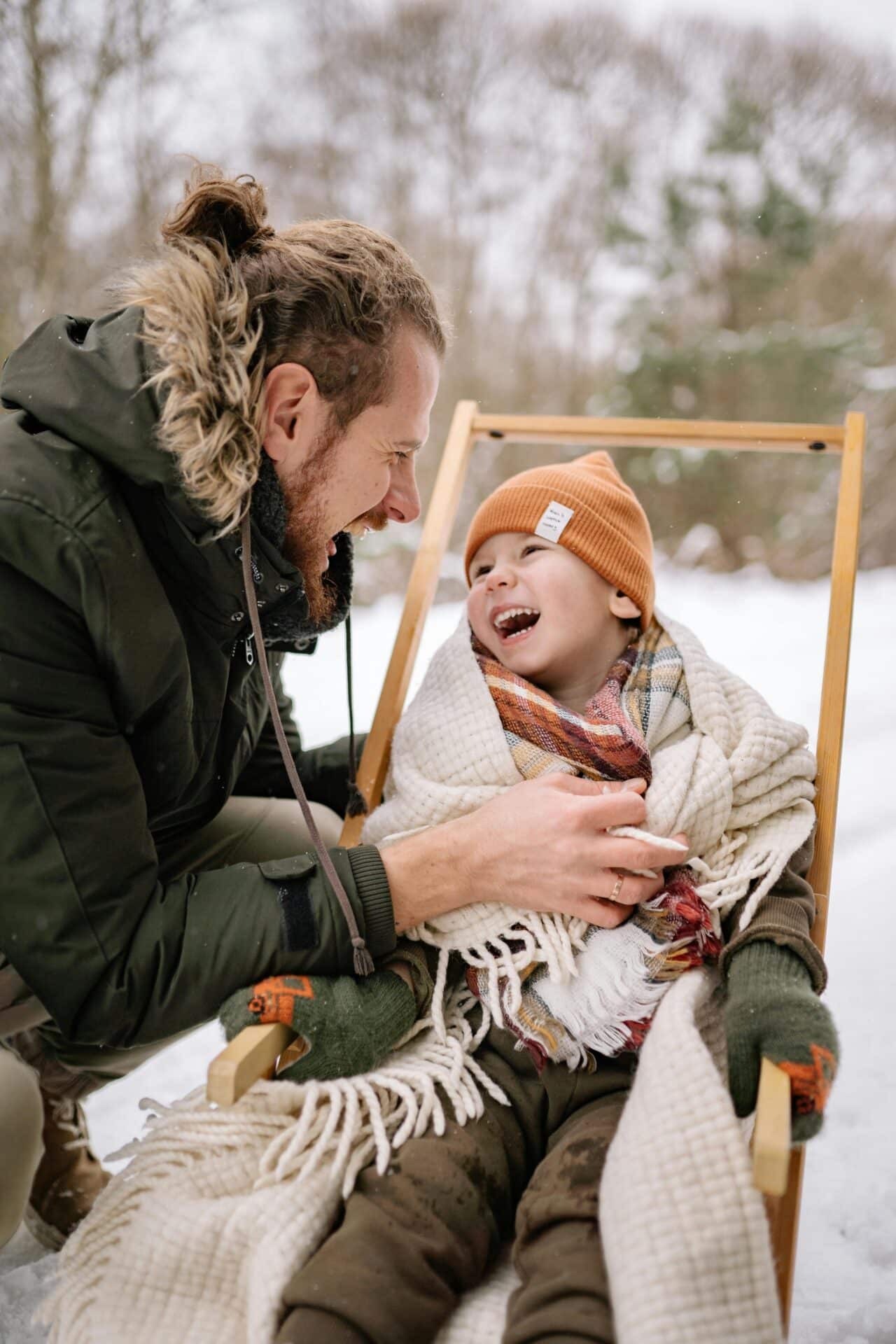 Smiling father and child bundle up in snowy weather