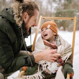 Smiling father and child bundle up in snowy weather